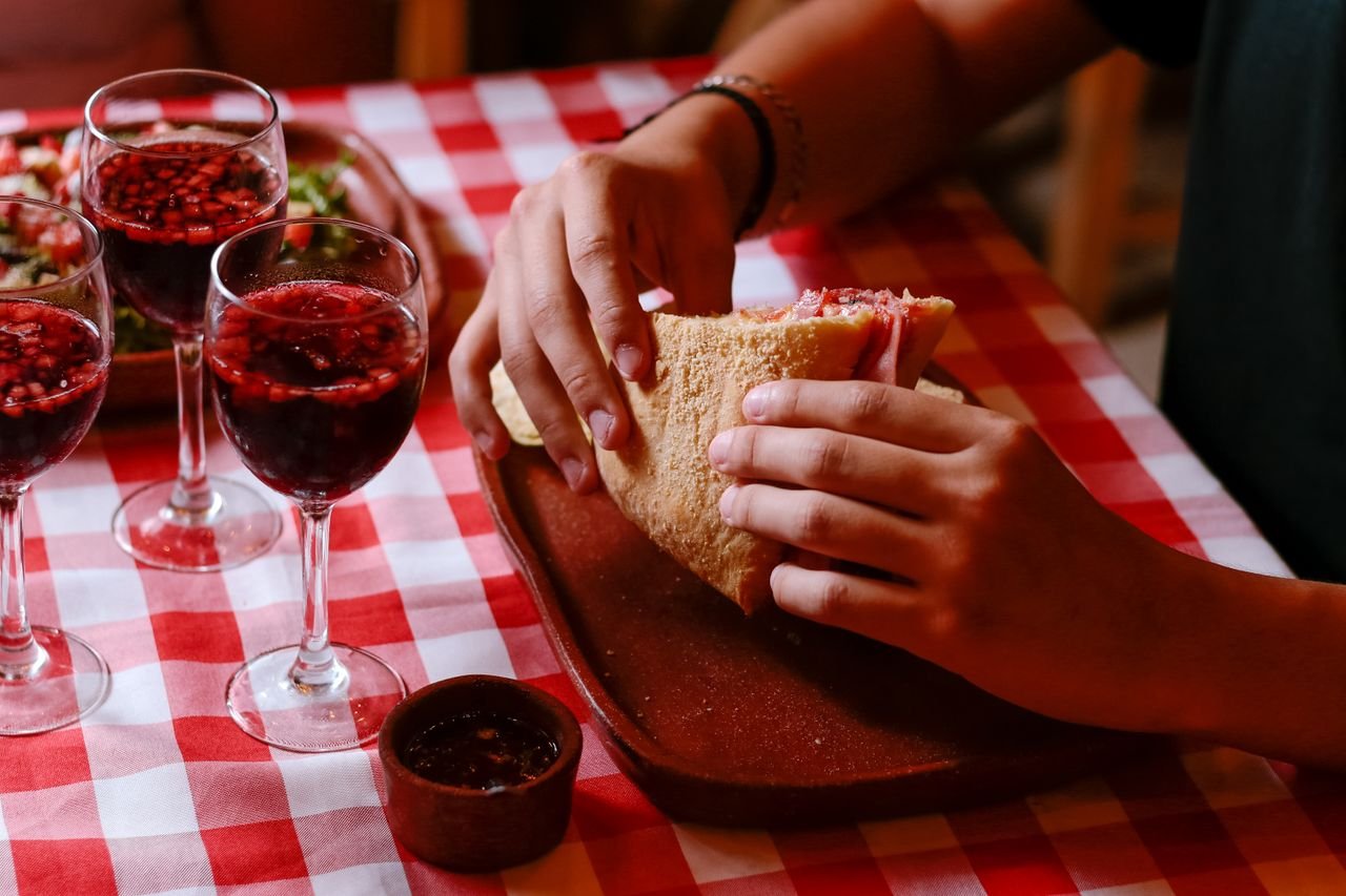 our-mission-01 A cozy dining scene with a sandwich and wine on a checkered tablecloth in Mexico.